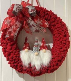 a red wreath with two gnomes hanging on it