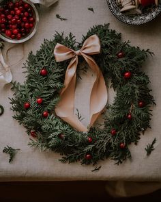 a christmas wreath on a table with cranberries and other holiday decorations around it