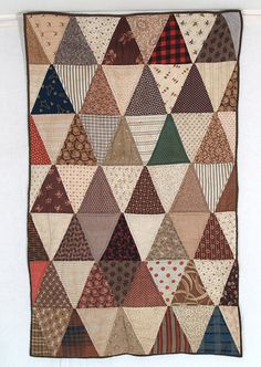 an old patchwork quilt with many different colors and patterns on the front, hanging up against a white wall