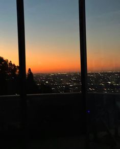 the sun is setting in front of some large windows with city lights on each side