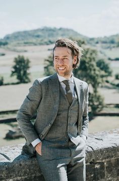 a man in a suit leaning on a wall