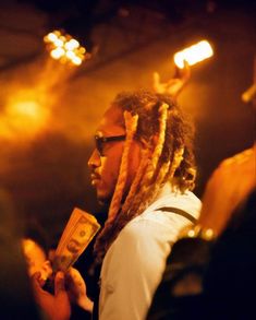 a man with dreadlocks holding money in front of his face at a concert