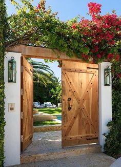 an open wooden door with flowers growing on it's sides and over the top