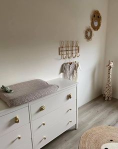 a baby's room with a crib, dresser and stuffed giraffe