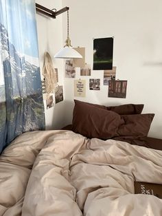 an unmade bed with brown sheets and pictures hanging on the wall above it in a bedroom