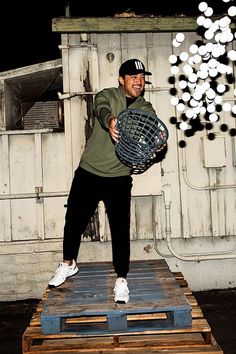 a man standing on top of a wooden pallet holding a metal object in his hands