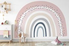 a child's room with pink, grey and white wallpaper that has a rainbow painted on it