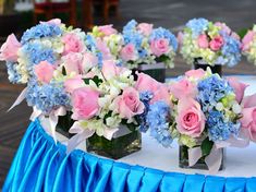 several vases filled with pink, blue and white flowers on top of a table