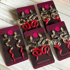 four pairs of red and silver earrings sitting on top of each other in front of a card