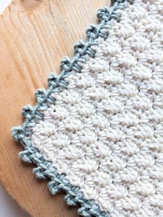 a crocheted dishcloth sitting on top of a wooden board