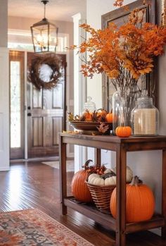 an entry way with pumpkins and flowers on the table