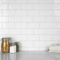 a kitchen counter topped with jars and containers filled with food next to a white brick wall