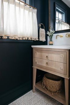 a white sink sitting under a bathroom mirror next to a wooden cabinet and counter top