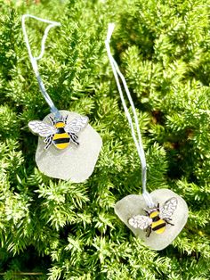 two glass bee ornament hanging from a tree