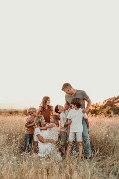 a group of kids and their parents standing in the middle of a field with tall grass