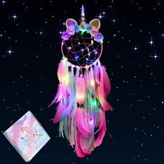 a pink and blue dream catcher with lights on it next to a notepad that says happy new year