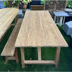 a wooden table and bench sitting on top of grass covered ground next to potted plants