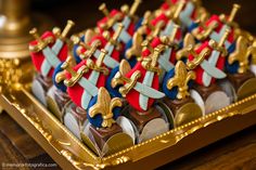 a tray filled with chocolates covered in gold and red decorations on top of a wooden table