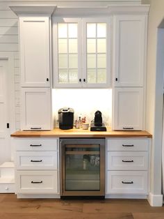 a kitchen with white cabinets and wood counter tops, an oven and coffee maker in the center