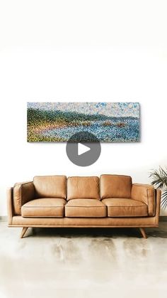 a couch sitting in front of a white wall with a painting on the wall behind it