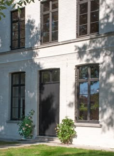 a white brick building with two windows and a black door on the side of it