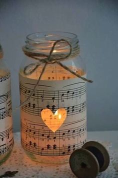 two mason jars with musical notes on them and a candle in the shape of a heart