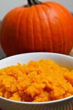 a white bowl filled with food next to a pumpkin