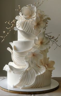 a three tiered white wedding cake with flowers on top