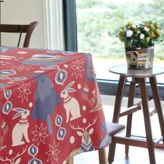 a table with a red cloth on it next to a wooden chair and small round table