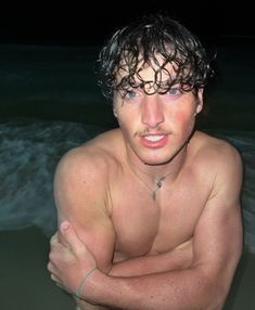 a shirtless man in the water with his arms crossed