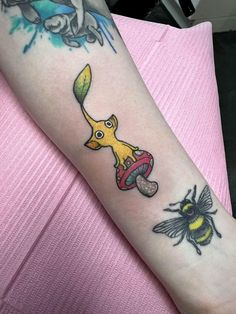 a woman's arm with tattoos on it, including a cartoon character and a bee