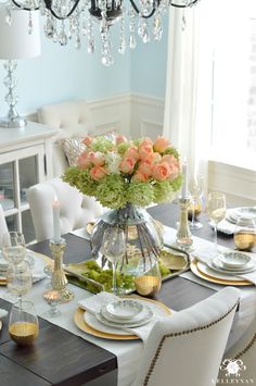 a dining room table is set with flowers and place settings