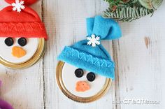 two snowmen with hats and scarves sitting on top of white wooden boards next to christmas decorations