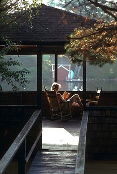 a woman sitting in a chair reading a book by the water's edge at night