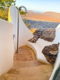 the stairs lead up to an outdoor shower area with rocks and trees in the background