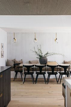 a dining room table and chairs in front of a wall with vertical stripes on it