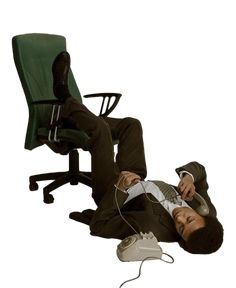 a man laying on the floor with headphones in his ears, next to an office chair