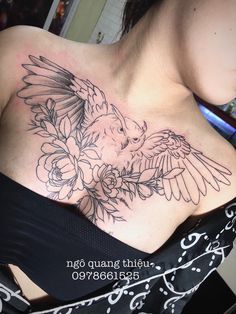 a woman's chest with a bird and flowers tattoo on her left side shoulder