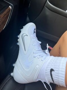 a person sitting in a car wearing white socks and holding a pair of nike sneakers