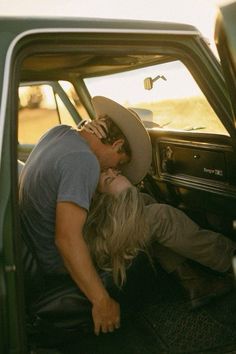 a man and woman kissing in the back of a pick up truck with their head inside