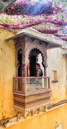 a man standing on the balcony of an old building with flowers growing all over it