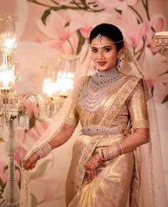 a woman in a white and gold bridal gown standing next to a chandelier