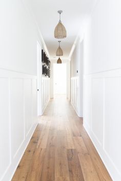 an empty hallway with white walls and wood floors