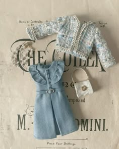 a doll outfit and purse sitting on top of a piece of paper