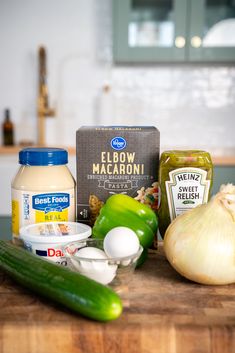 the ingredients to make this dish are displayed on a cutting board, including onions, cucumbers, garlic, and mayonnaise