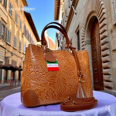 This bag has been made of the best genuine leather by local master crafters of Florence in Italy, designed for women who only accept premium Italian quality and luxury leather bags and modern Italian fashion. . Sizes: Width:   31 cm/12.25 inch Height:  22 cm/8.75 inch Depth:   11 cm/4.25 inch Color:  Brown . The story of this bag:  In the heart of Florence, where tradition and innovation intertwine, there existed a workshop renowned for its exquisite leather goods. Among the treasures crafted wi Italian Leather Bag As Gift, Italian Leather Bag As A Gift, Italian Leather Bags In Cognac, Italian Leather Bags In Cognac Color, Handmade Leather Tote Bag, Stylish Leather Bags, Handmade Leather Bags, Luxury Leather Bag, Flower Purses