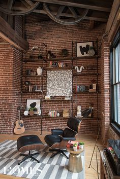 a living room filled with furniture and a brick wall mounted book shelf next to a window