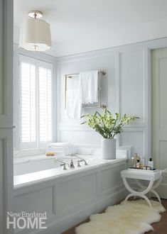 a bath room with a tub a sink and a chair next to a window in it