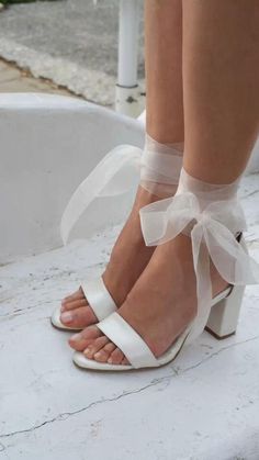 a woman's legs wearing white high heels and sheer gauzed bow ties