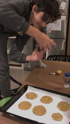 a young boy is making cookies in the kitchen